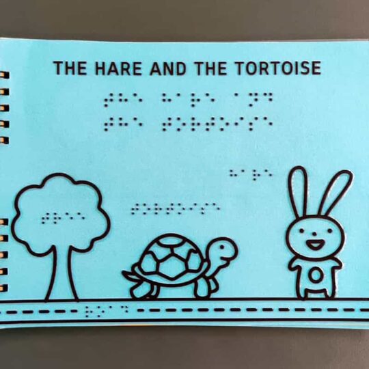 Front page of The hare and the tortoise Braille book showing tree, hare and tortoise